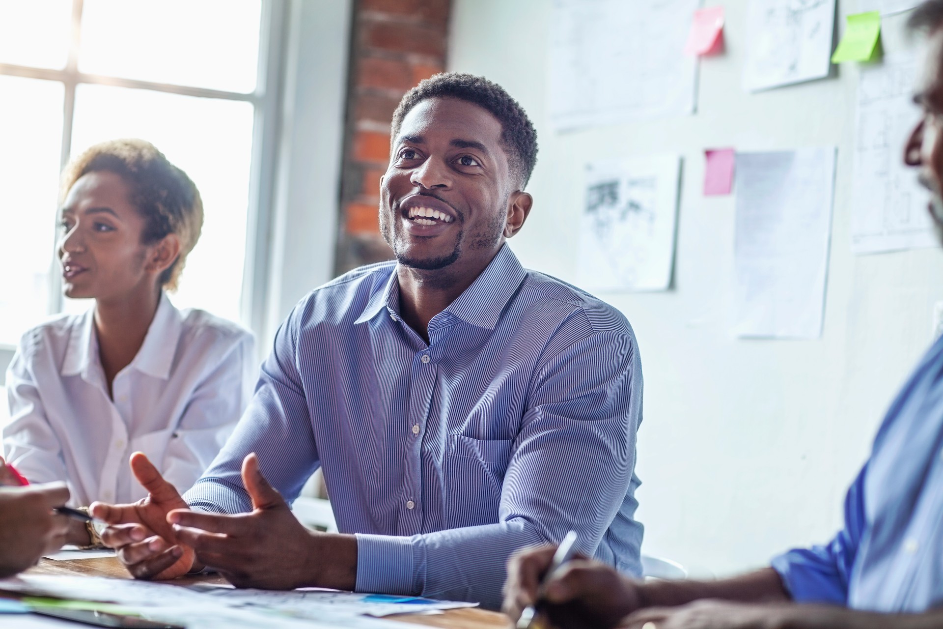 Black mid adult man talking with coworkers in meeting in bright office