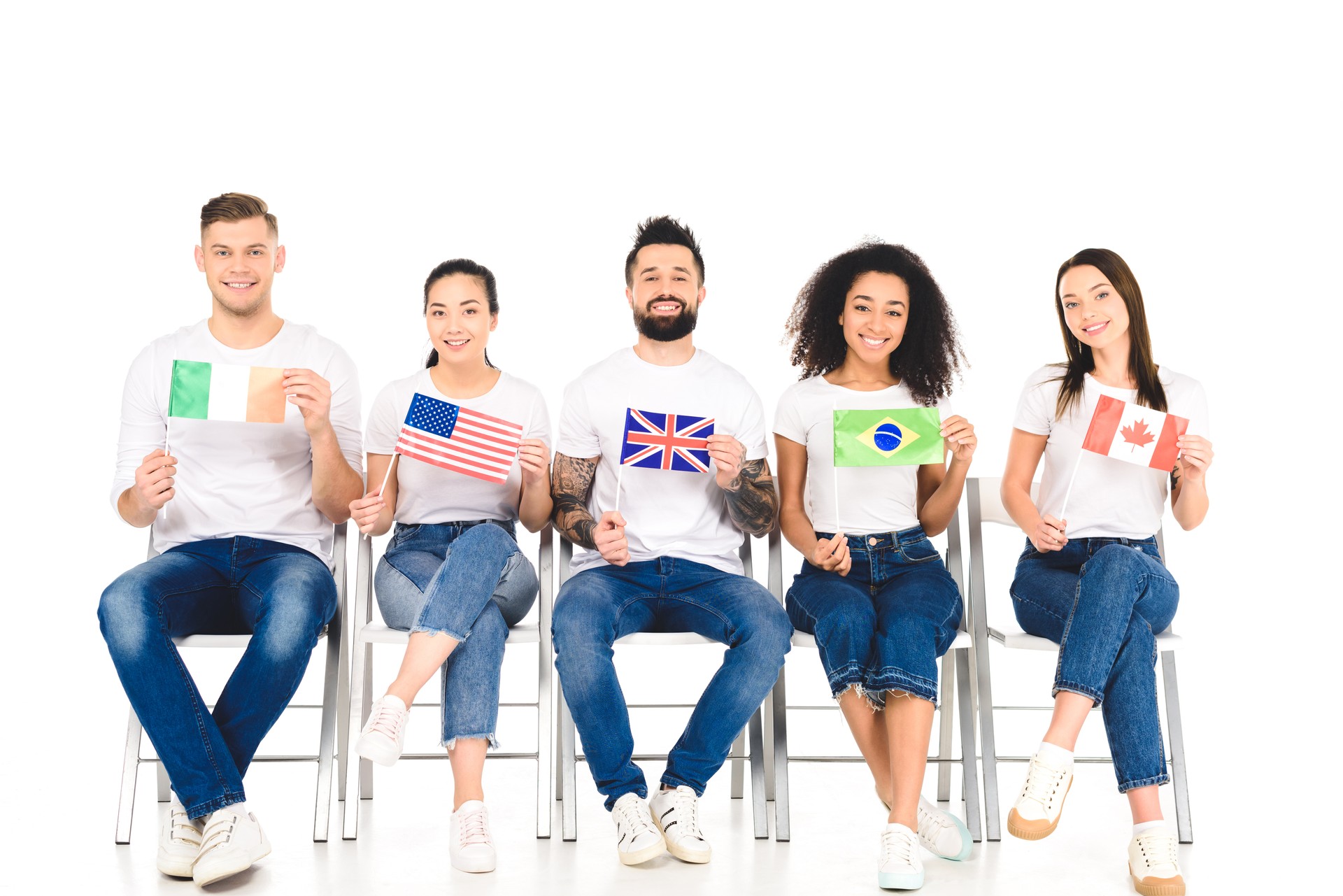 multicultural group of people sitting on chairs with flags of different countries isolated on white